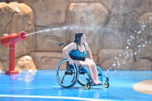 Girl in wheelchair playing on a splash pad